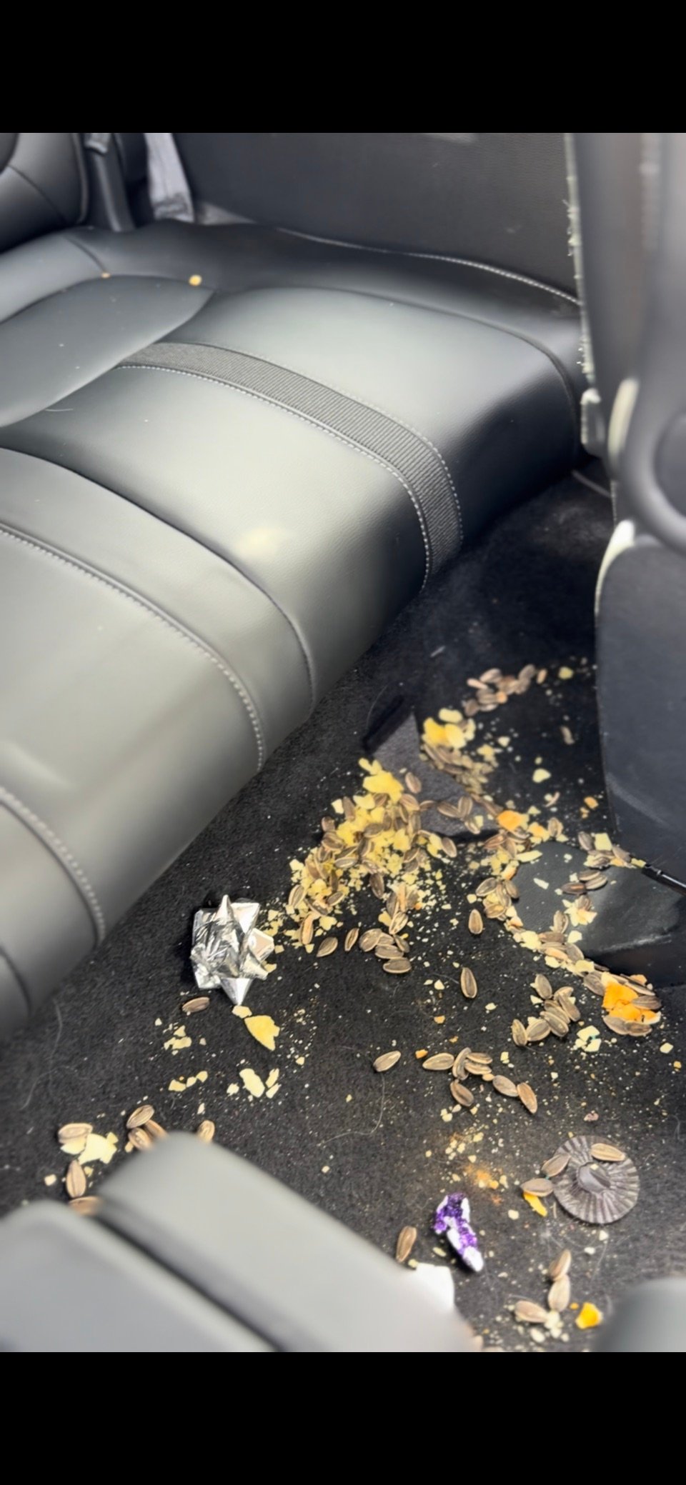 Rear passenger floor with crumbs and debris before interior detailing