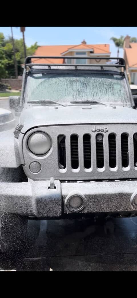White Jeep covered in foam during an exterior wash