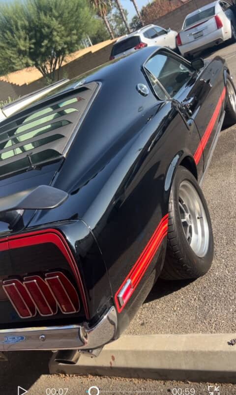 Rear quarter of a glossy black Mustang with red stripes