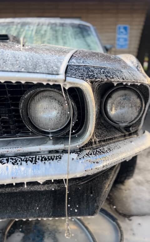 Foam wash on the grille and headlights of a black classic Ford Mustang